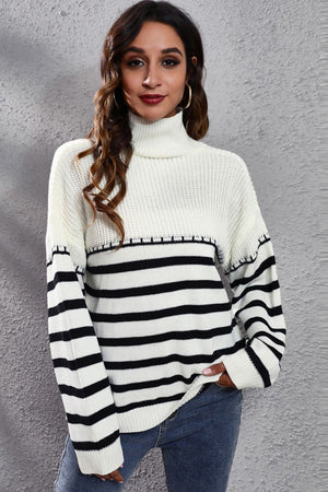 Turtleneck knit sweater with black and white Breton stripes and a ribbed texture.