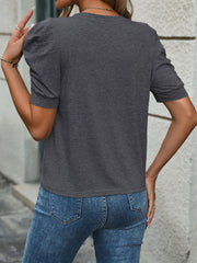 Dark gray jersey top with puffed short sleeves and a crew neck, styled with blue jeans.