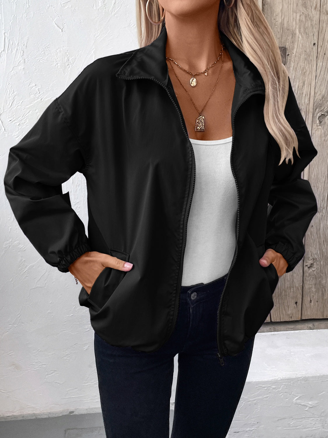 Black nylon bomber jacket with drawstring hem and zippered pockets.
