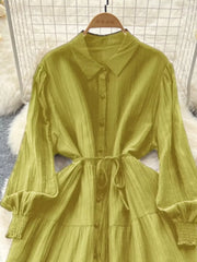 Yellow-green textured tiered long sleeve button-down dress with cinched waist and smocked cuffs.