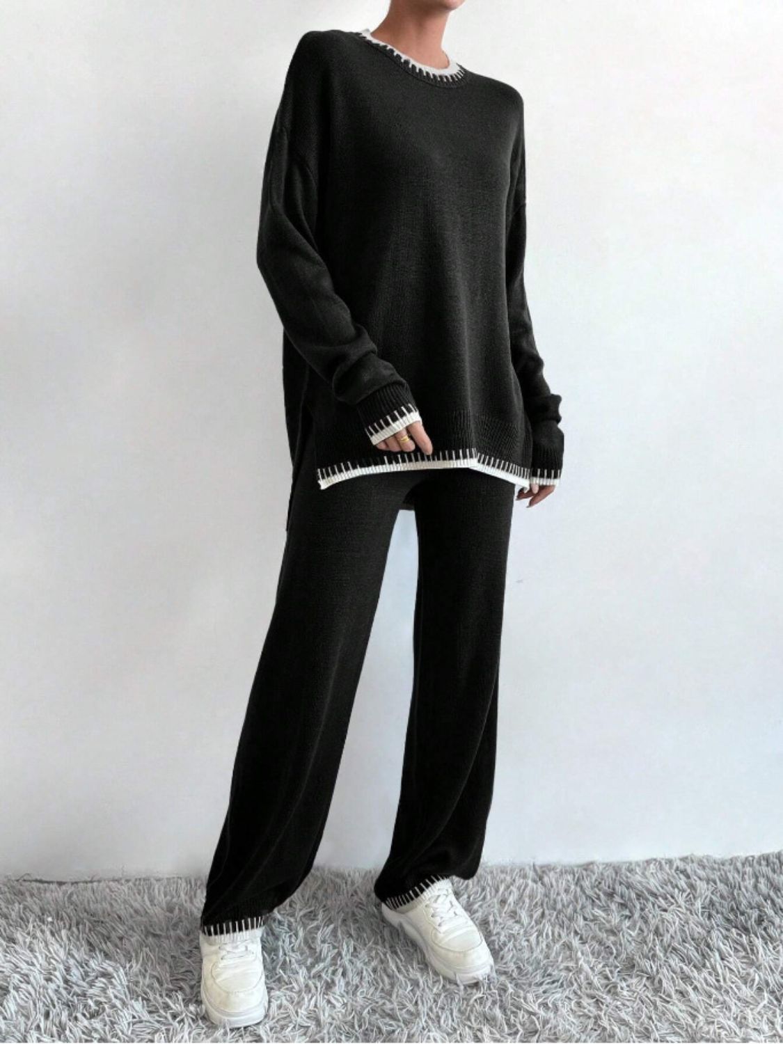 Black acrylic knit loungewear set with white contrast stitching on neckline, cuffs, and hem.