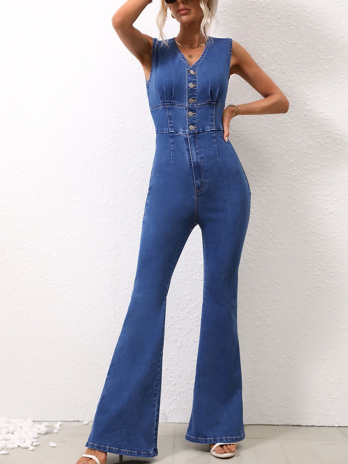 Buttoned bodice flare leg denim jumpsuit in dark blue cotton with a V-neck and sleeveless design.