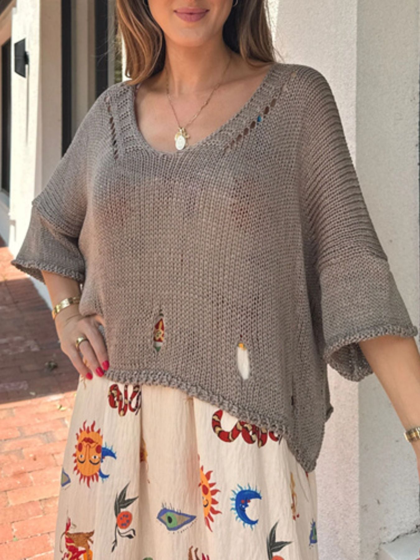 Distressed knit pullover sweater with cutout details and asymmetrical hem.