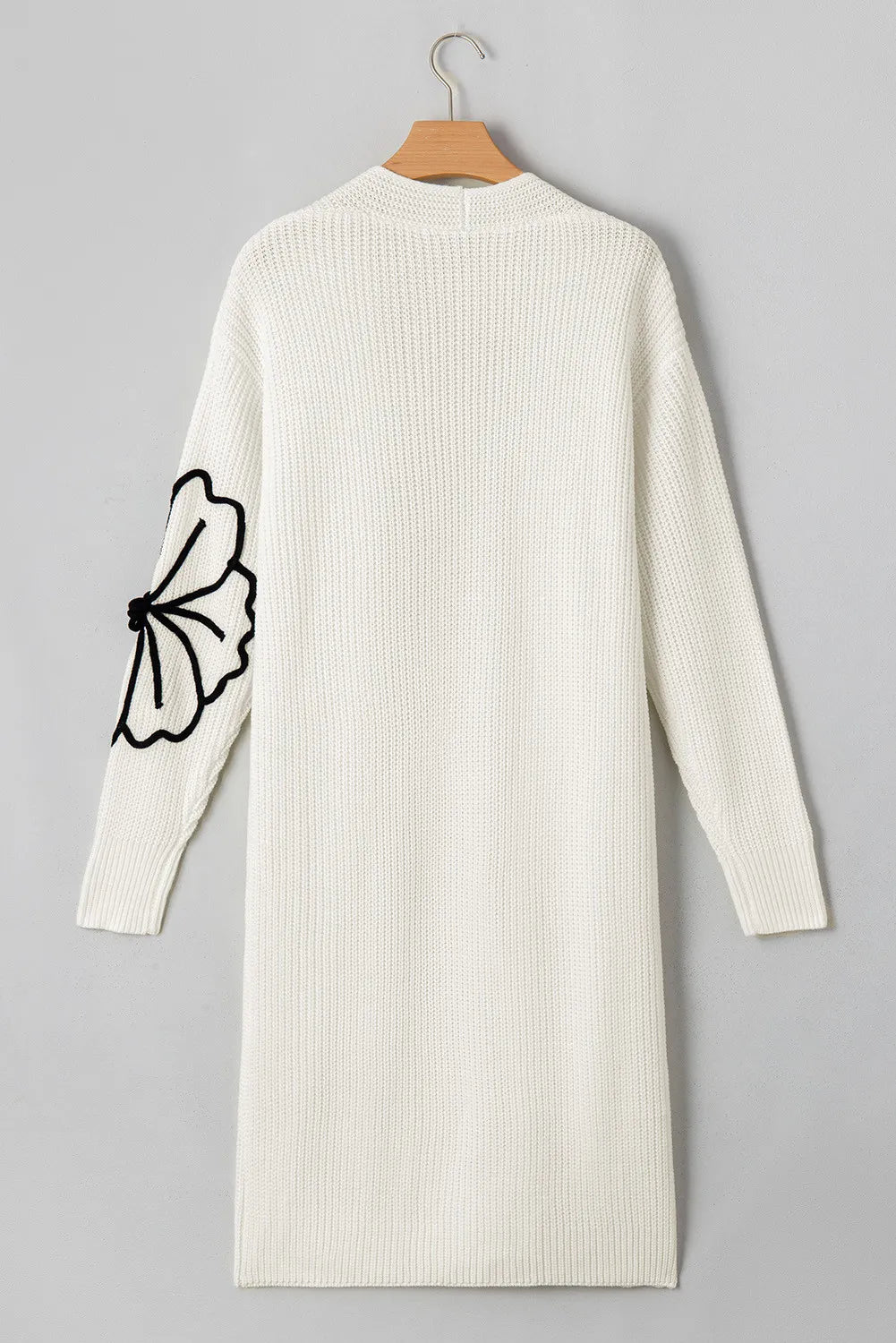 Ivory knit maxi cardigan with black floral appliqué on sleeve. Open front, long sleeve.
