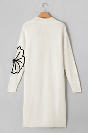 Ivory knit maxi cardigan with black floral appliqué on sleeve. Open front, long sleeve.