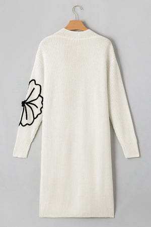 Ivory knit maxi cardigan with black floral appliqué on sleeve. Open front, long sleeve.