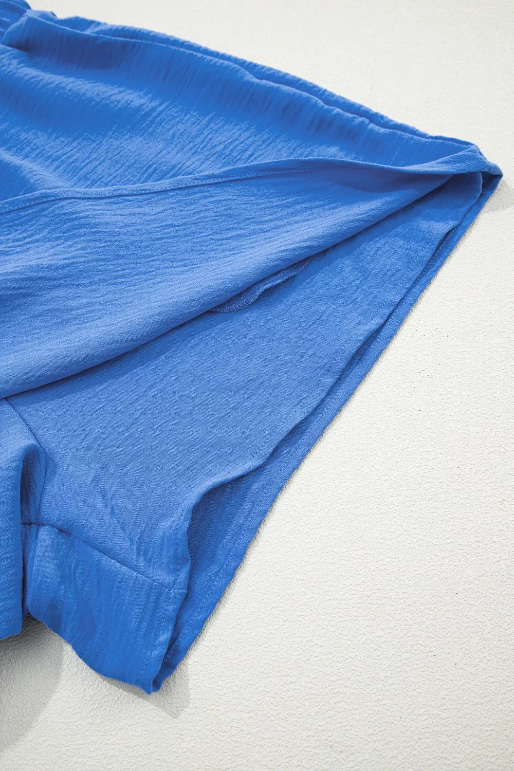 Blue textured drawstring shorts showing hem detail and relaxed fit.