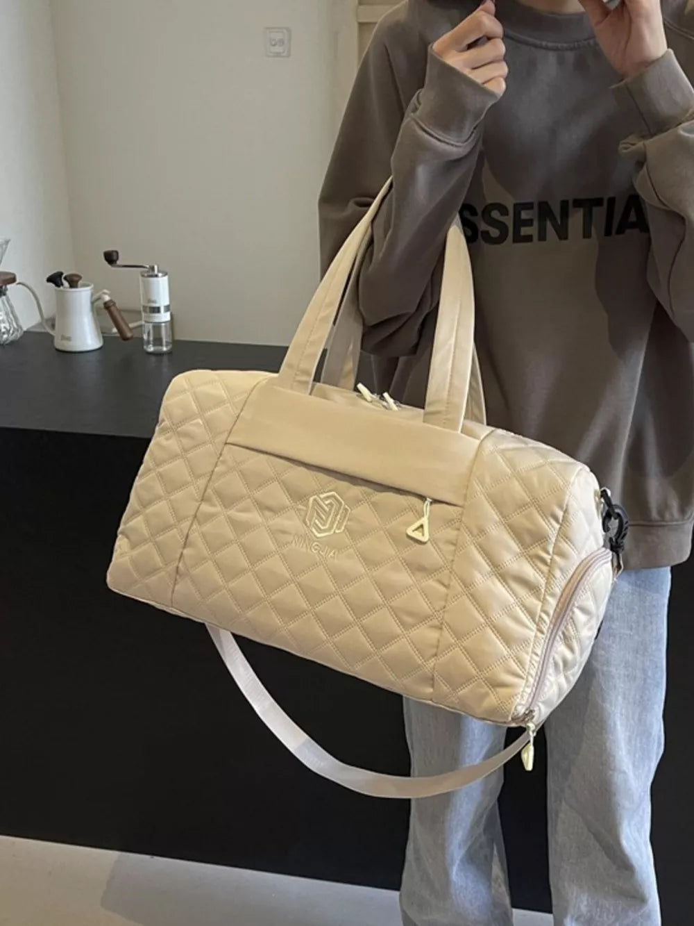 Diamond-stitched beige quilted duffel bag with adjustable strap and top handles