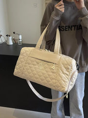 Diamond-stitched beige quilted duffel bag with adjustable strap and top handles