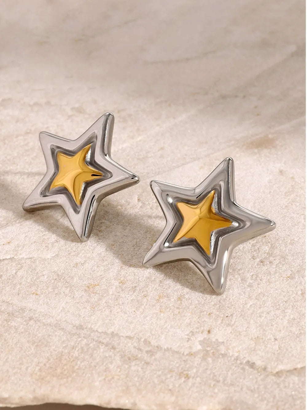 Sculpted starburst stud earrings in silver and gold feature a layered star design.