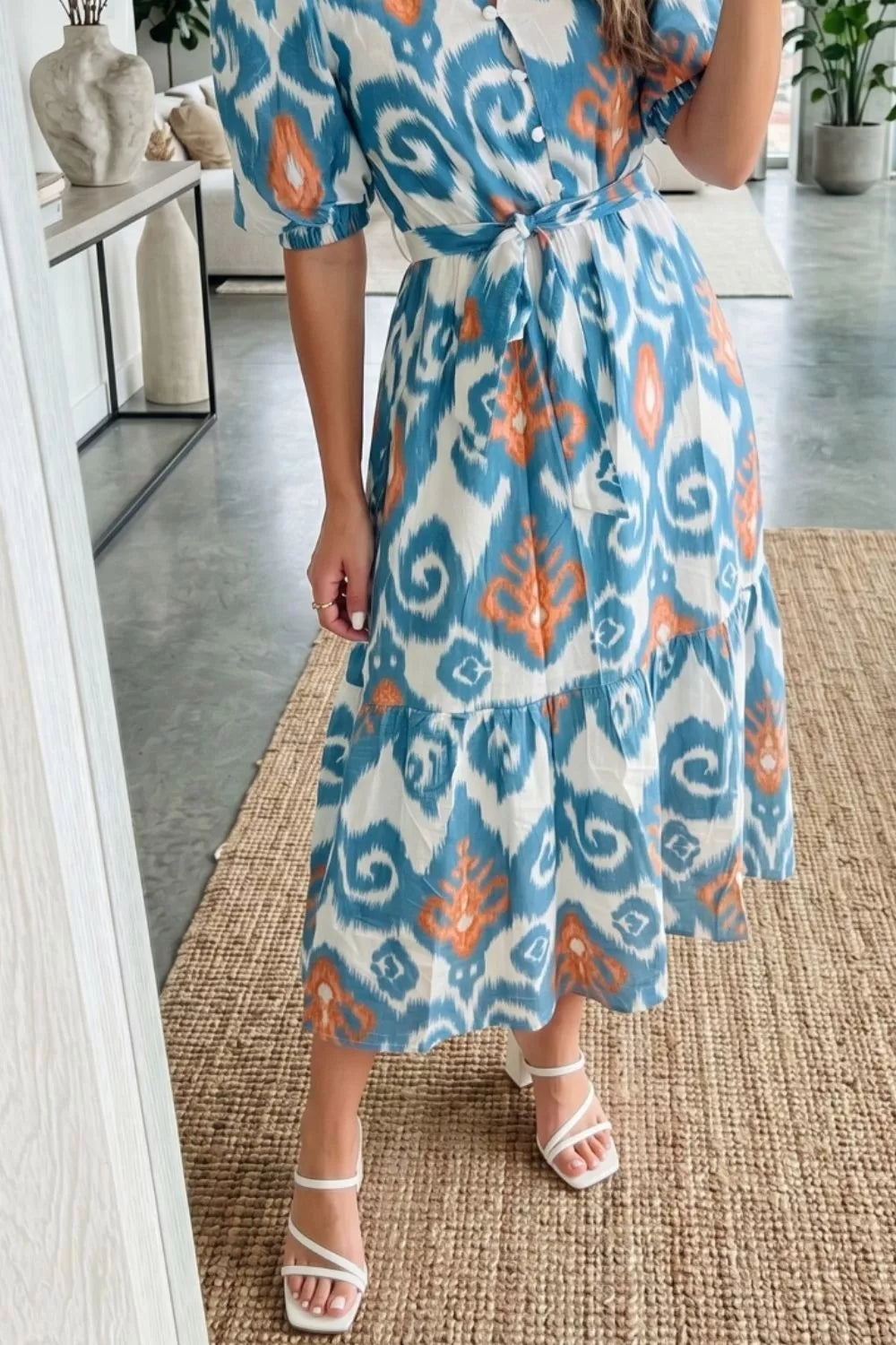 Ikat floral midi dress with puff sleeves, tie waist, and tiered skirt in blue, orange, and white cotton.