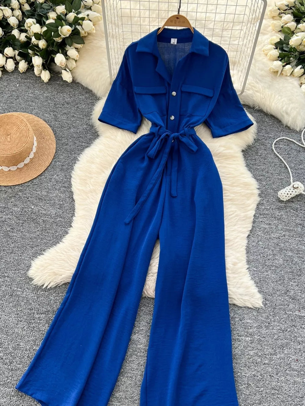 Blue belted wide-leg maternity jumpsuit with pockets and buttoned chest pockets.