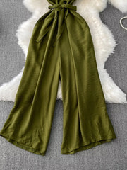 Green V-neck wide leg jumpsuit with tie belt and button detail.