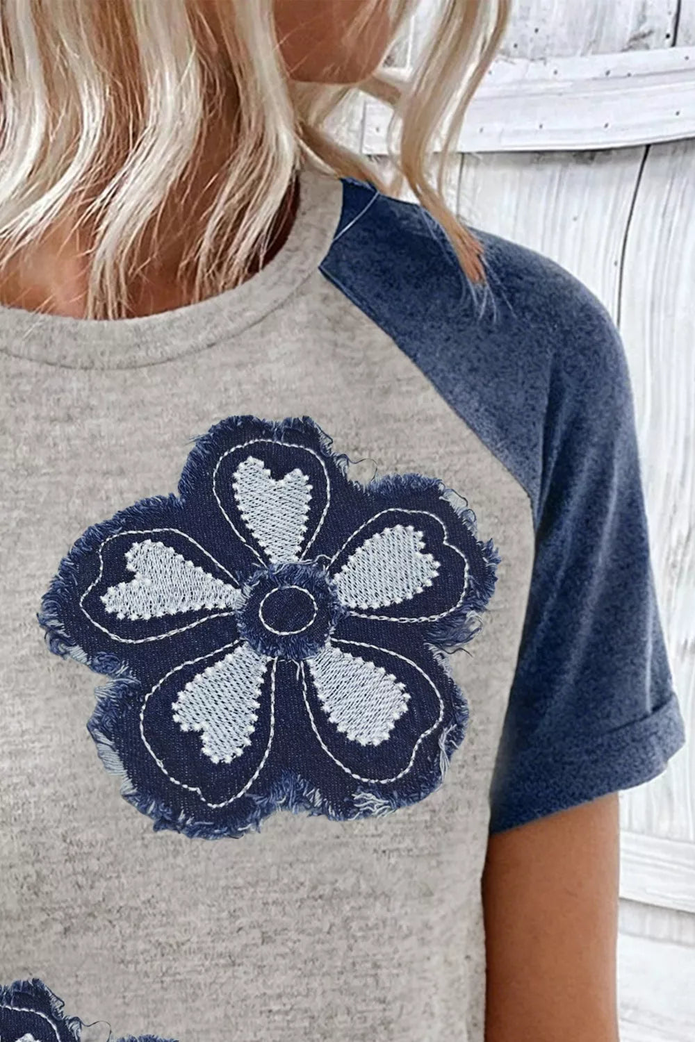 Gray t-shirt with denim floral applique and blue raglan sleeves.