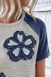 Gray t-shirt with denim floral applique and blue raglan sleeves.