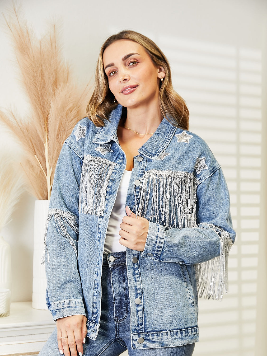 Light denim trucker jacket with star patches and silver fringe detail on shoulders and chest.