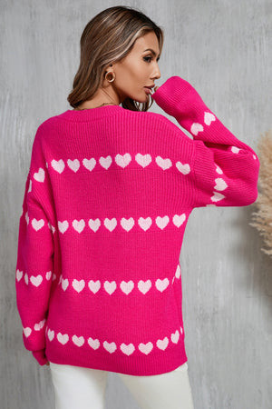 Hot pink knit pullover sweater with white heart stripes and long sleeves.