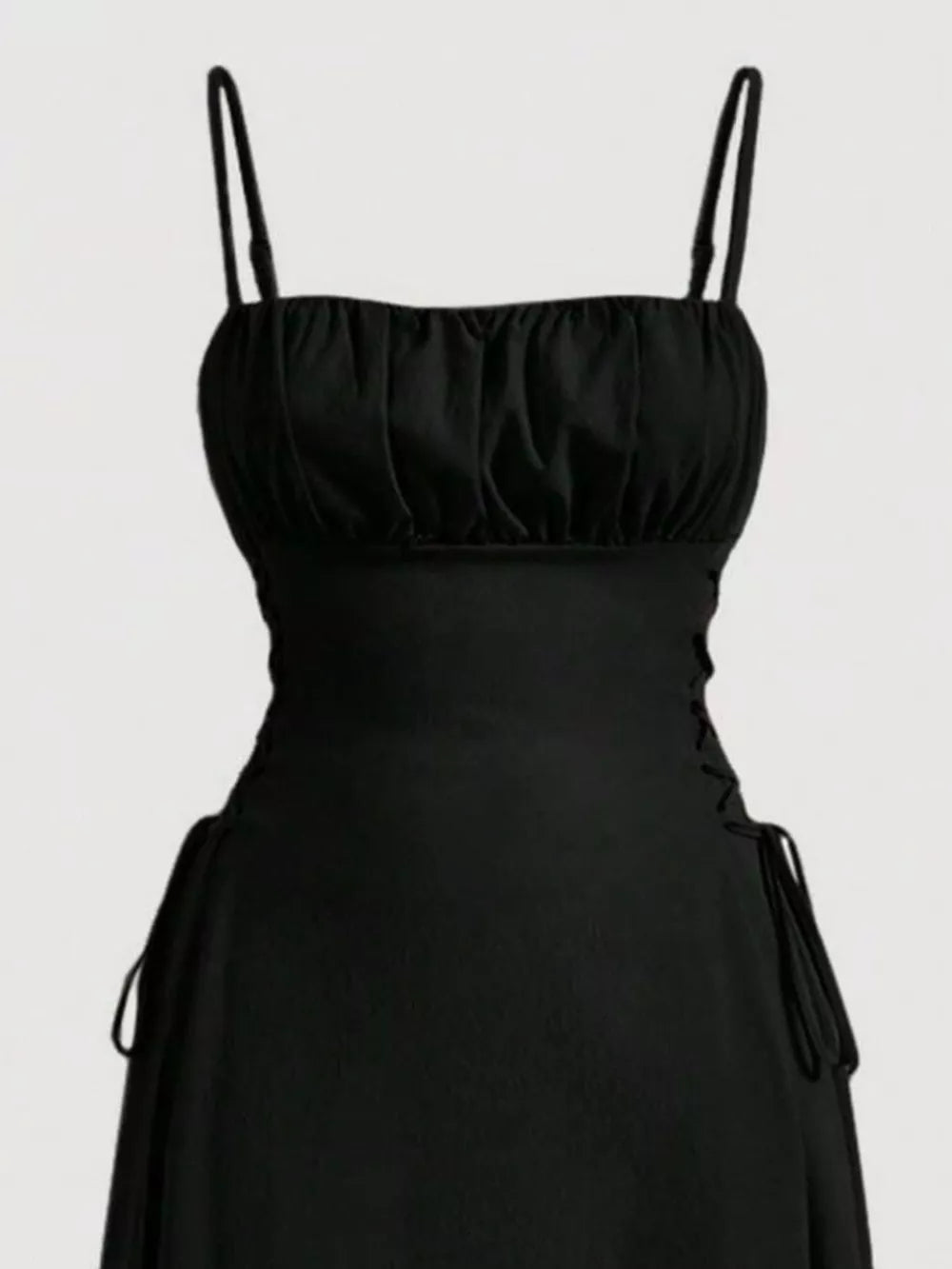 Black cami dress with ruched bodice and crisscross lace-up sides.