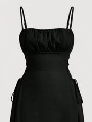 Black cami dress with ruched bodice and crisscross lace-up sides.