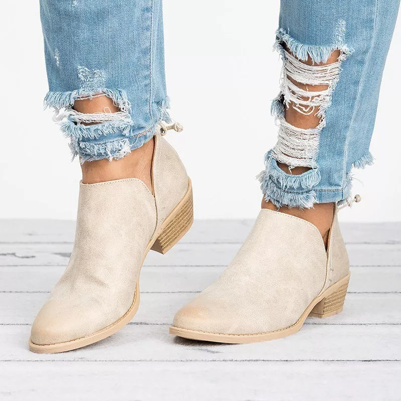 Beige V-cut pointed toe block heel boots with side cutouts styled with distressed jeans.