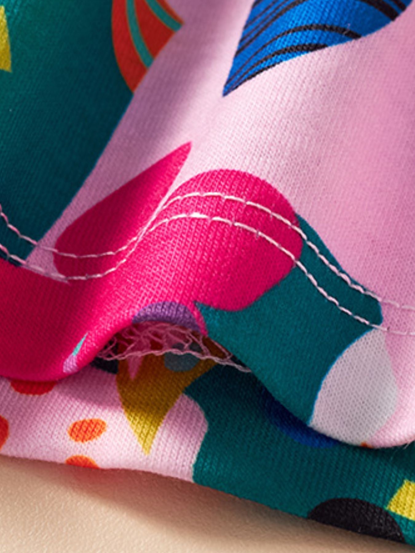 Toddler dress with playful jungle print, pink fabric, and white stitching detail.