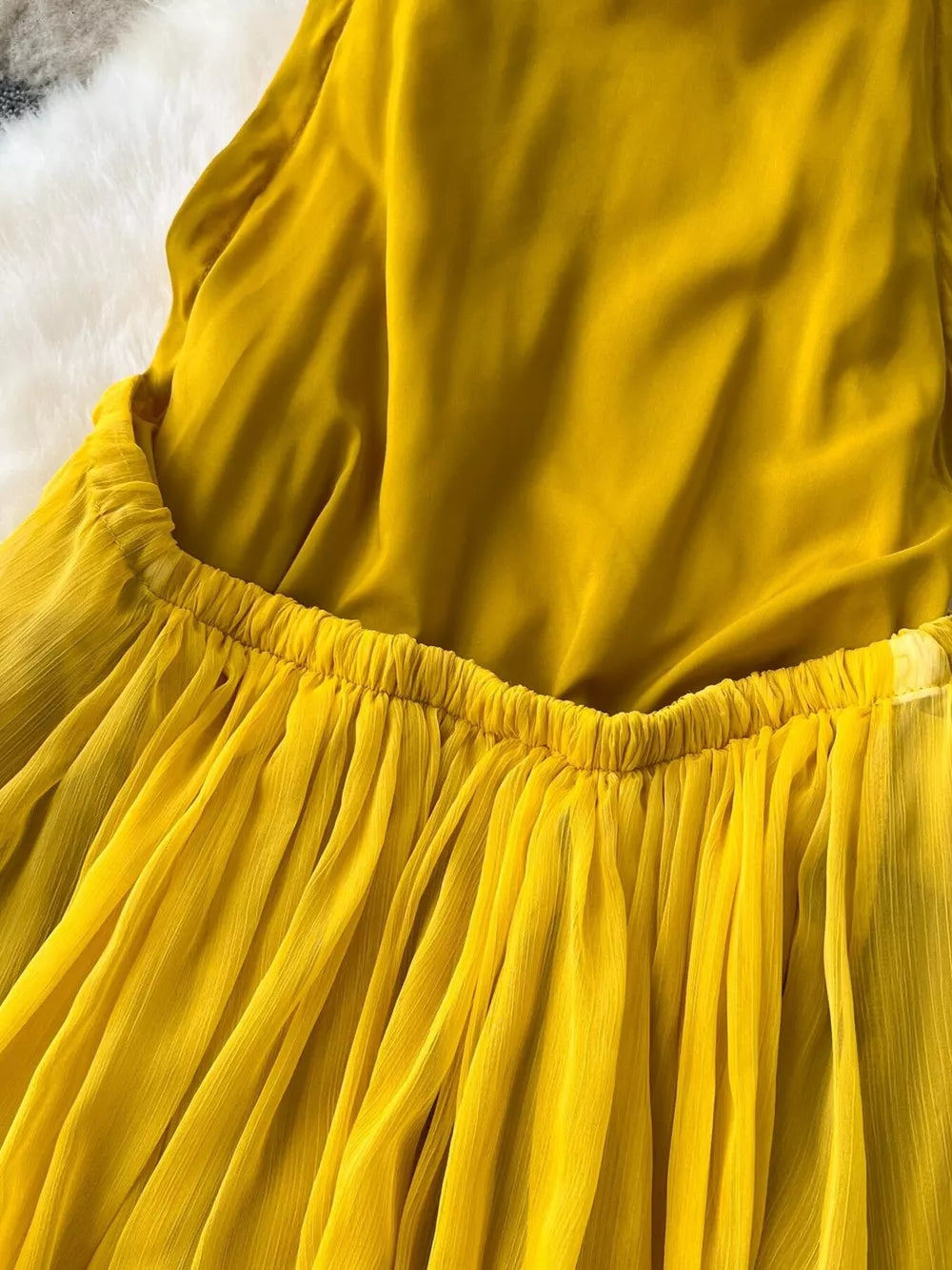 Yellow halter dress with a gathered elastic waist and flowing chiffon skirt.