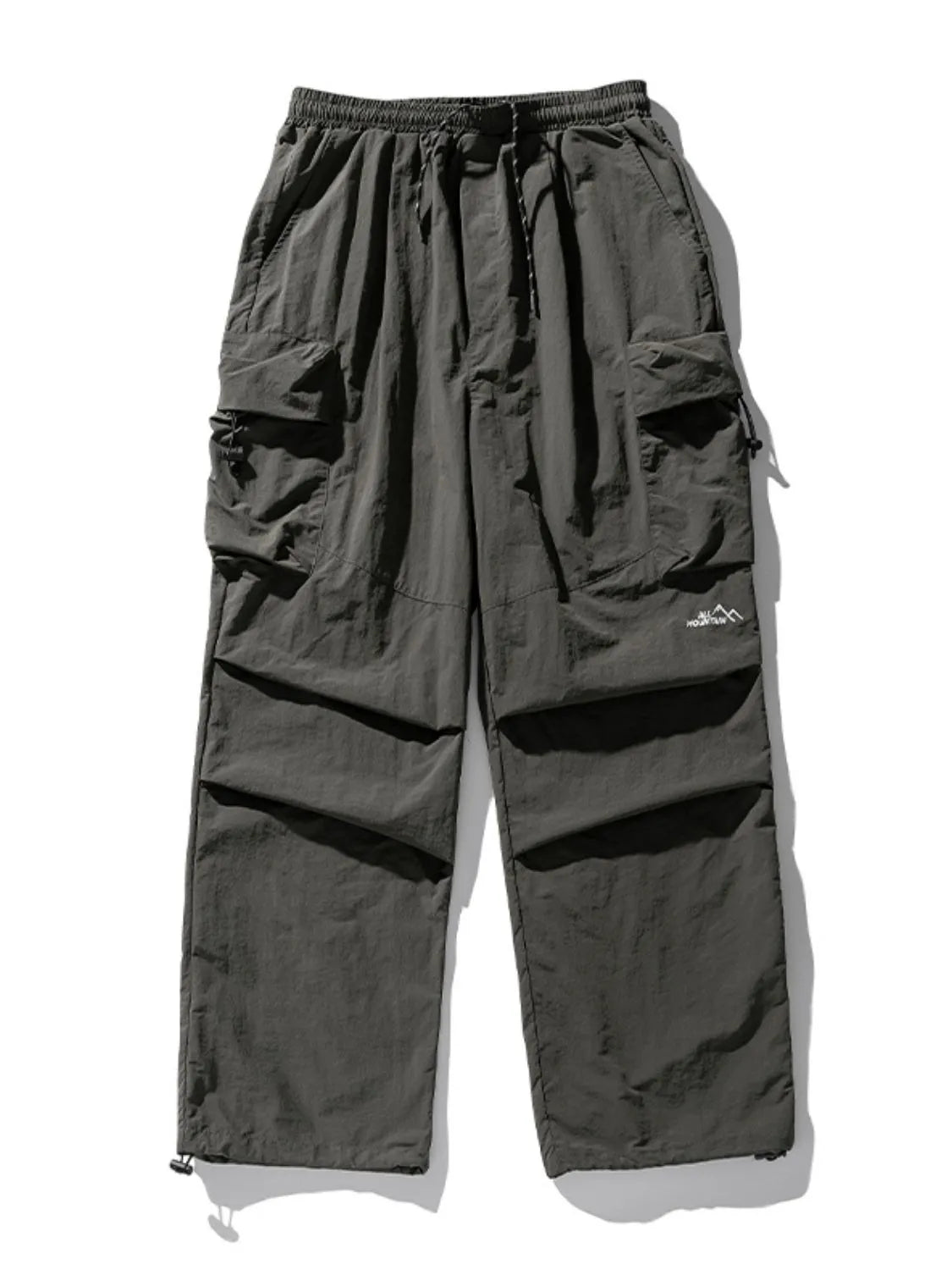 Oversized dark gray utility cargo pants with multiple pockets and drawstring waist.