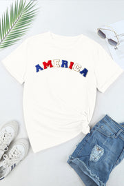 White embroidered "America" tee with rolled sleeves and a knotted hem.