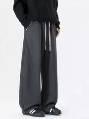 Dark gray wide-leg sweatpants with white drawstring and contrast stitching.