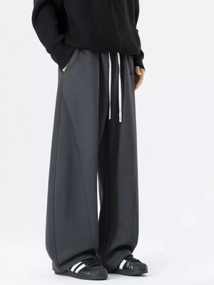Dark gray wide-leg sweatpants with white drawstring and contrast stitching.
