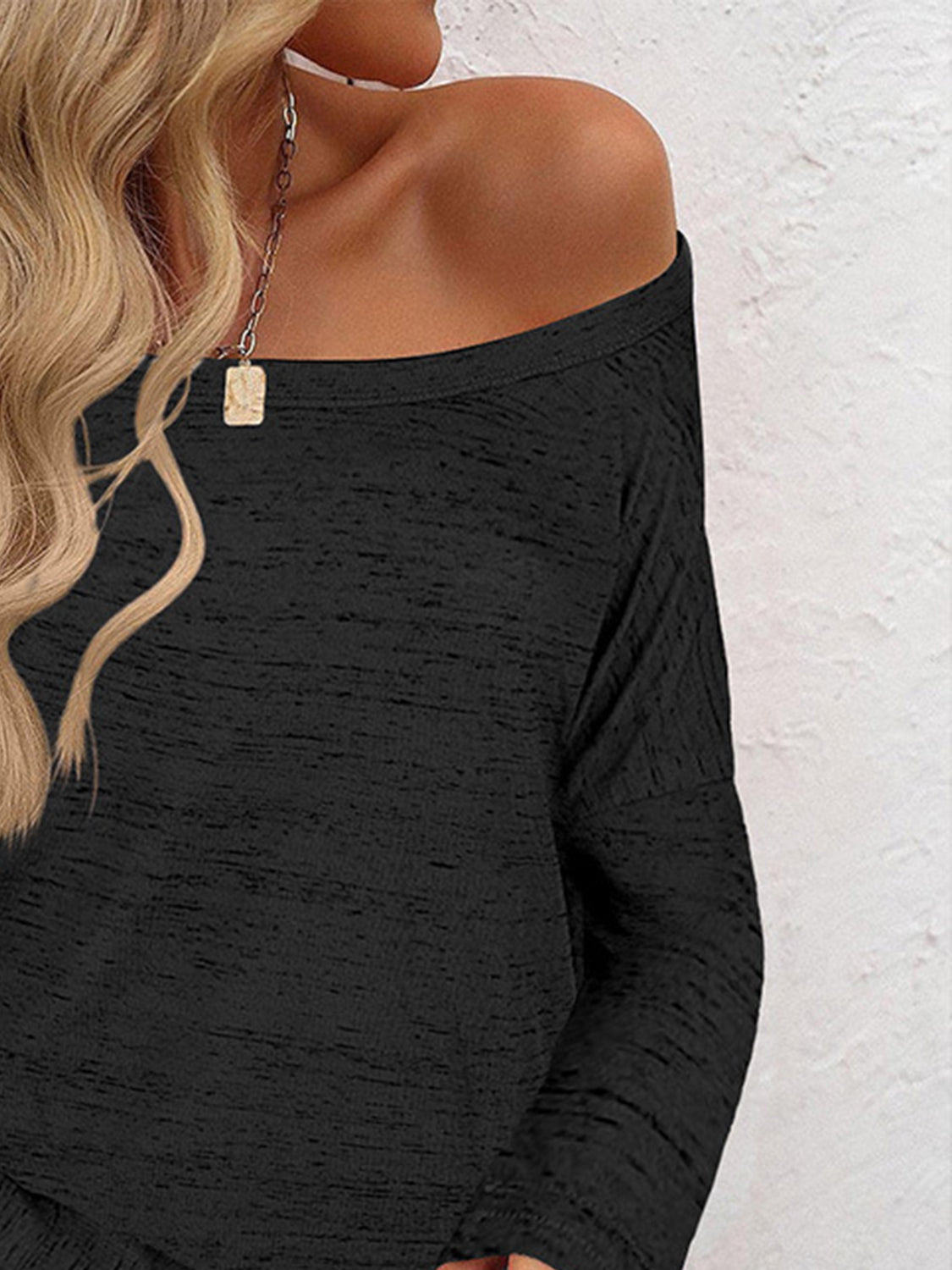 Black off-the-shoulder heathered knit top with long sleeves.