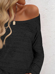 Black off-the-shoulder heathered knit top with long sleeves.
