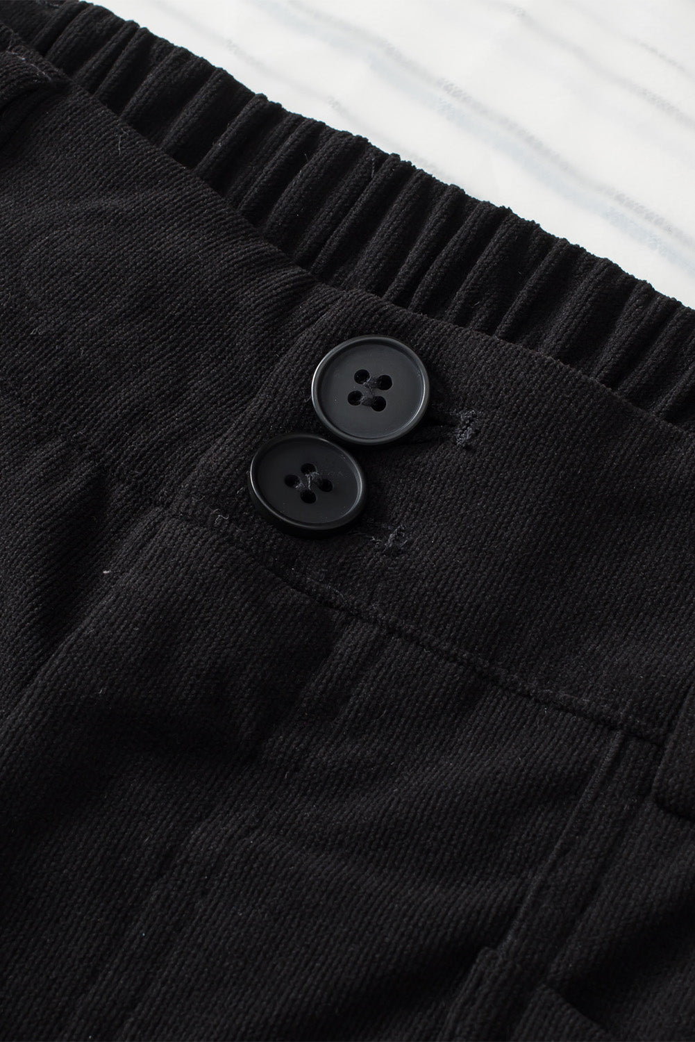 Black seamed front wide leg trousers with button detail and elastic waistband.