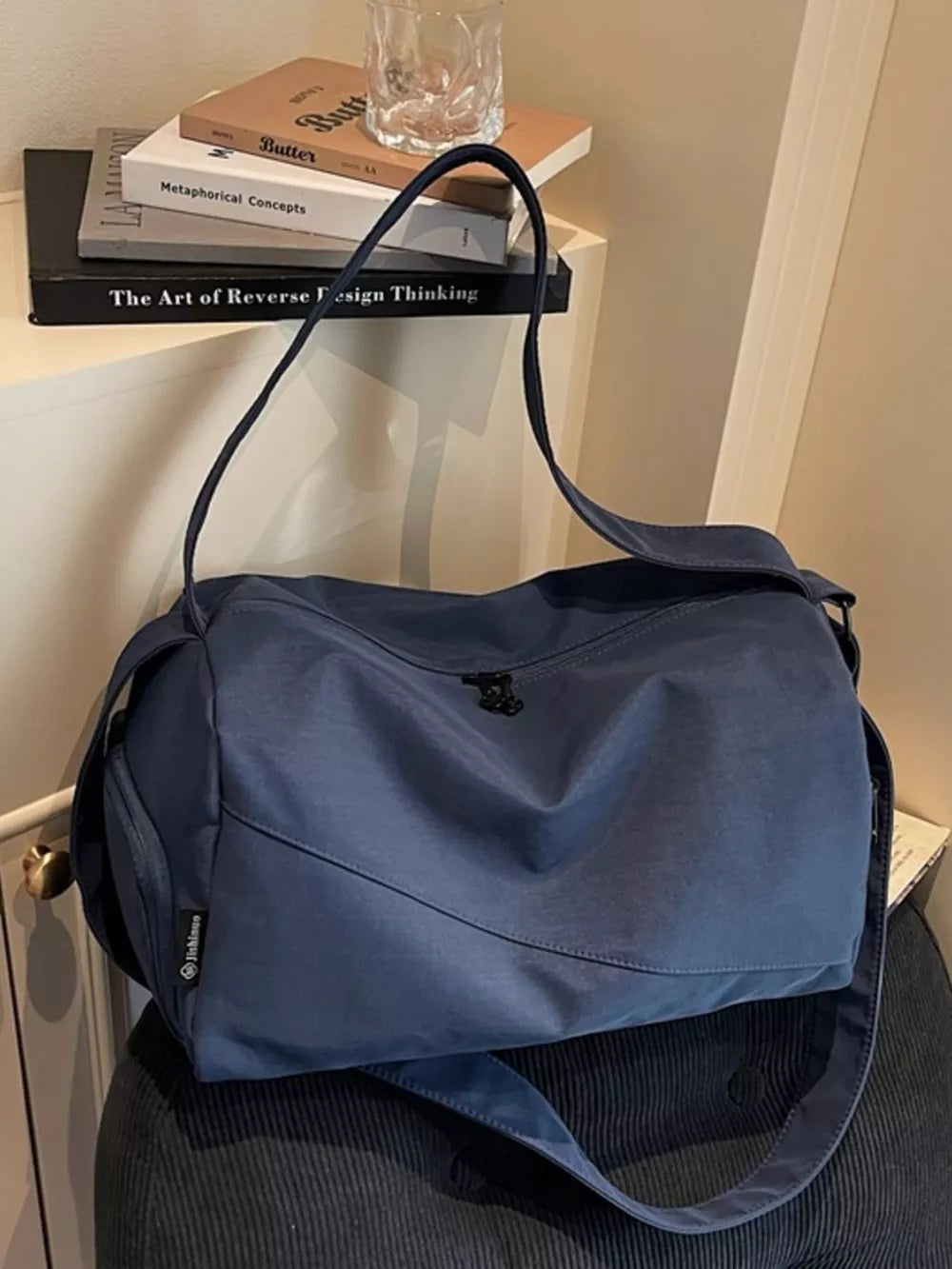 Blue Oxford cloth travel bag with adjustable strap and zippered closure.