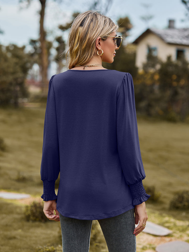 Navy peplum sleeve blouse with gathered yoke and smocked cuffs.