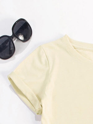 Cream t-shirt with rolled sleeves and round neck, styled with sunglasses.