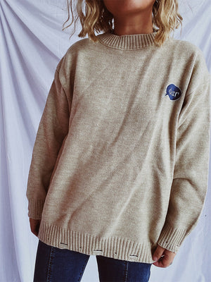 Relaxed knit sweater in dark gray or tan, acrylic, with embroidered character detail.