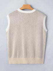 Sleeveless knit sweater vest in beige with white trim and ribbed hem.