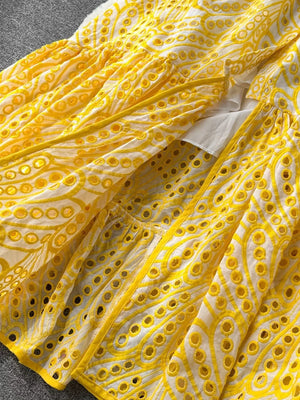 Yellow lace-embroidered tiered cami dress with eyelet details and a white underlayer.