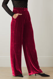 Burgundy velvet palazzo trousers with high waist and pockets, wide leg cut.