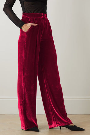Burgundy velvet palazzo trousers with high waist and pockets, wide leg cut.