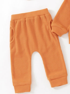 Orange waffle knit toddler pants with pockets and ribbed cuffs.