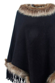 Black knit poncho with faux fur trim and fringe detail.