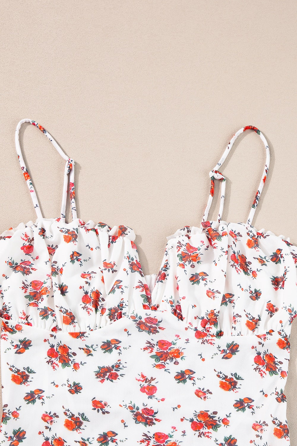 White floral bustier camisole with ruffle trim and adjustable straps.