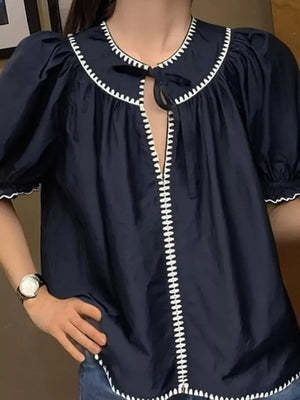 Navy polyester blouse with scalloped collar, tie neck, and white contrast stitching.