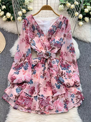 Pink floral ruffle hem wrap mini dress with cinched waist and long sleeves.