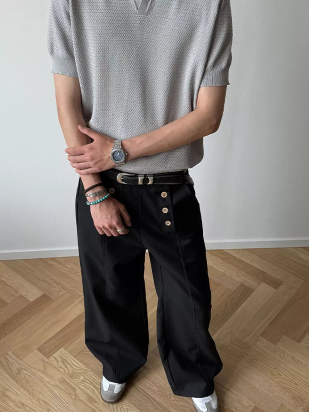Black high-waisted wide leg pants with button detail and front seam.