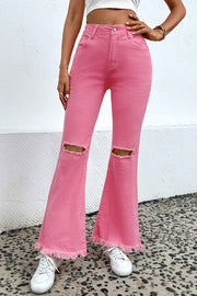 Pink flare jeans with distressed knees and raw hem, styled with white sneakers.