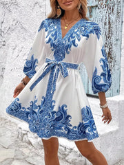 Blue paisley print mini dress with V-neck, billowy sleeves, and waist tie.