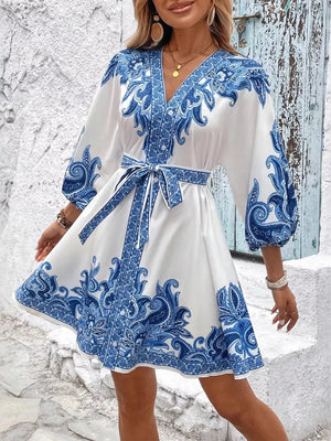 Blue paisley print mini dress with V-neck, billowy sleeves, and waist tie.